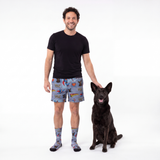 Man wearing superman pajama shorts with a dog on a white background