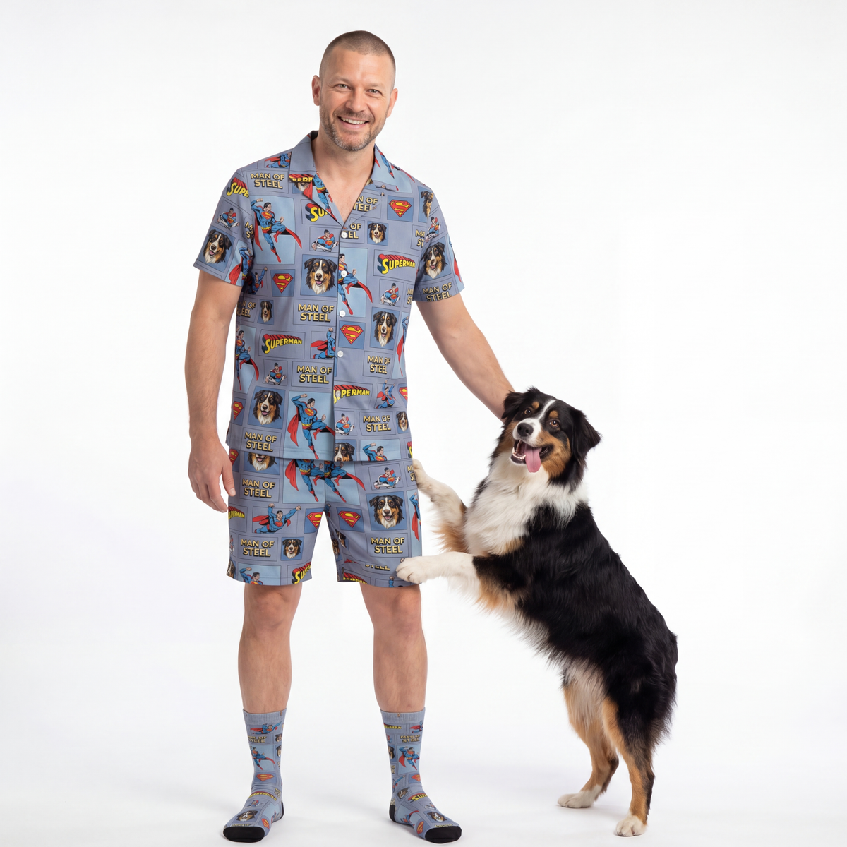 Man wearing superman-themed pajamas with a dog on a white background