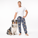 Man wearing blue plaid pajama pants with dog pattern, standing next to a dog on a white background