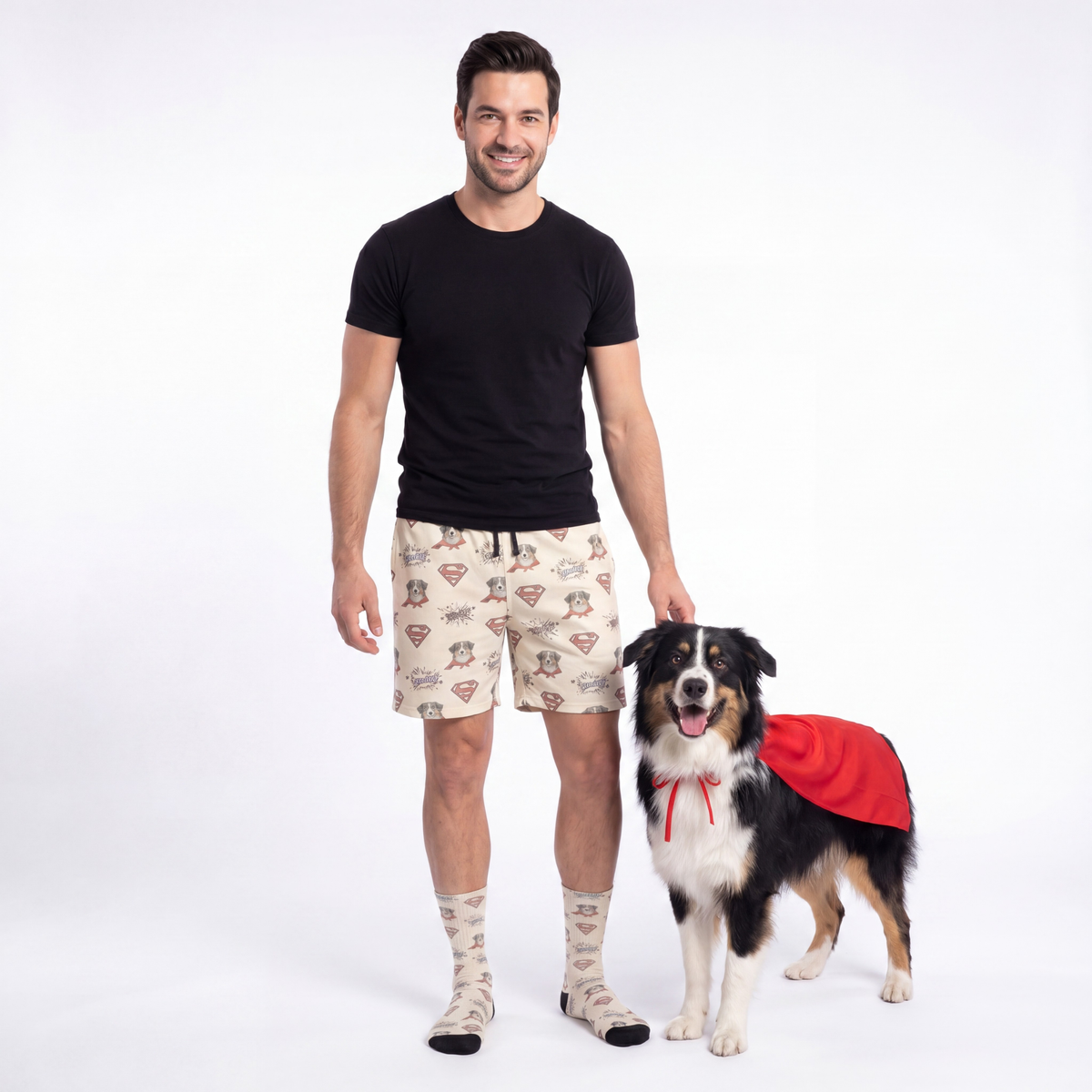 Man wearing Superman shorts with a dog in a red cape on a white background