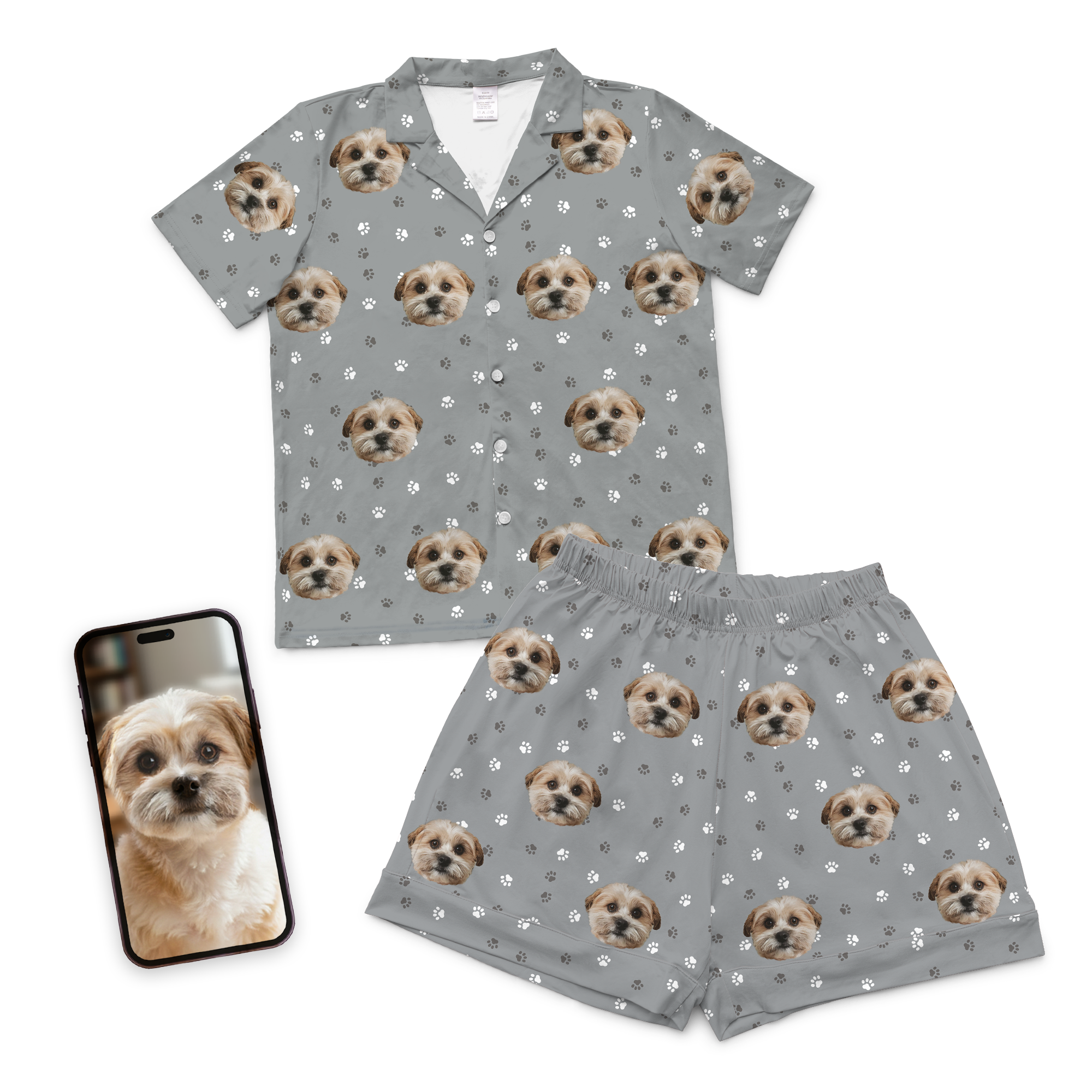 Custom pet face pajamas in gray short button-down set with repeating dog portraits and paw print pattern, shown with phone displaying original dog photo