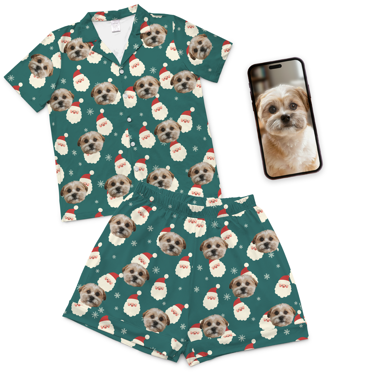 Matching green Christmas pajama set featuring an all-over pattern of a small dog’s face alongside Santa Claus illustrations and snowflakes. The set includes a short-sleeve button-up shirt and matching shorts. A smartphone displaying the same dog’s photo is placed to the right of the outfit.