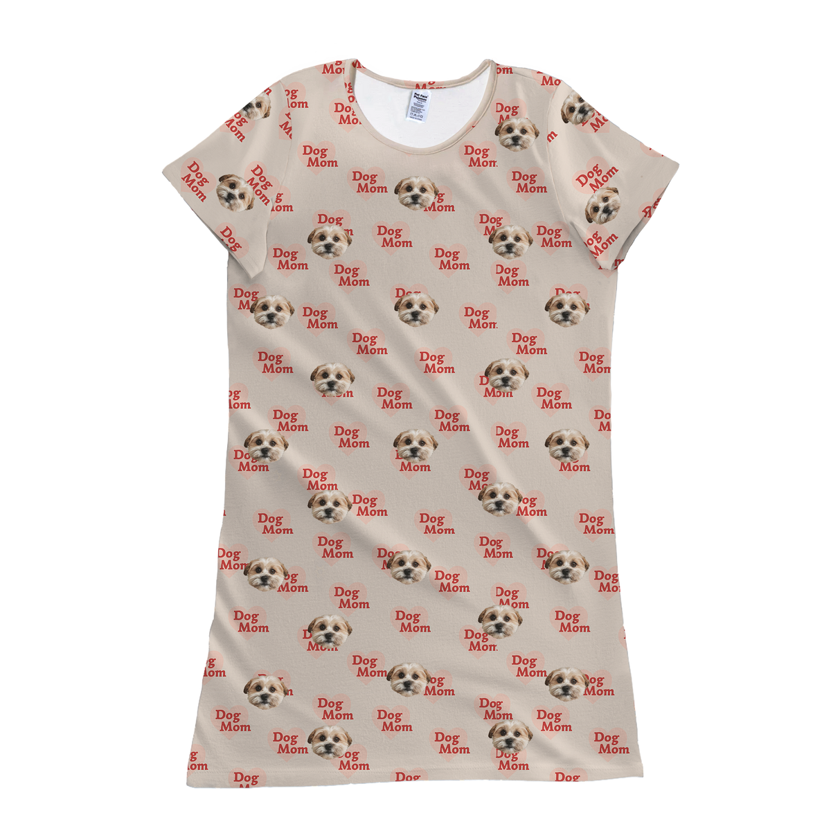 A product shot of a short-sleeve pajama or nightgown style T-shirt dress in a light tan or beige color. The fabric is patterned with repeated prints of a dog's face and the phrase "Dog Mom" in red text on a small pink banner.