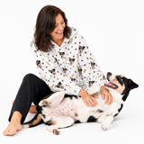 Paws and bones hoodie theme – person in dog-print hoodie playing with black, white, and tan dog.