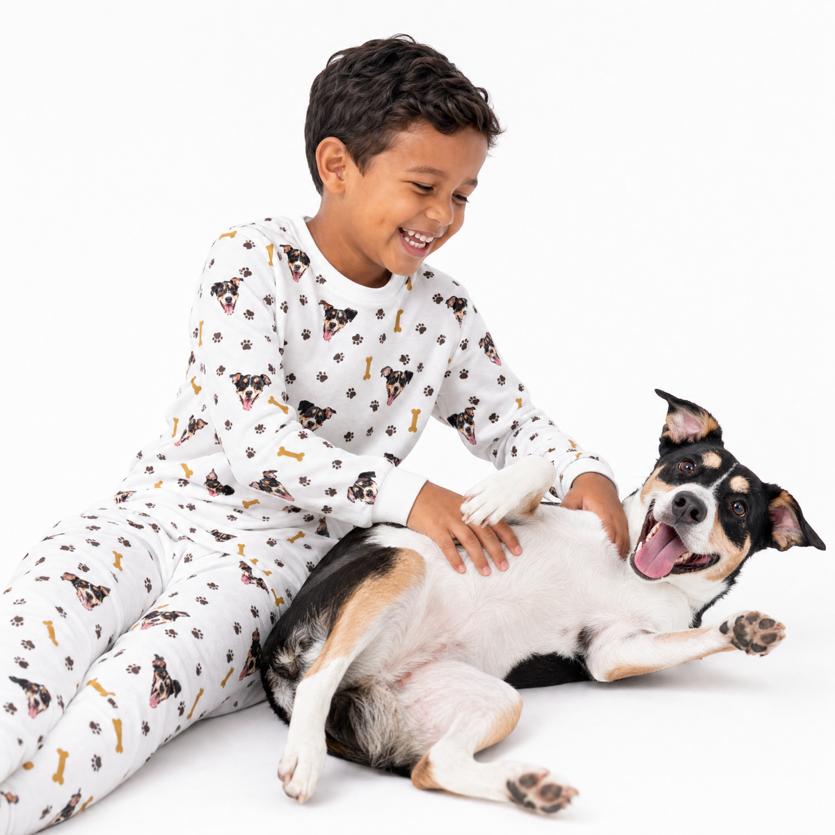 Child in white jogger pajamas playing with a dog on a white background