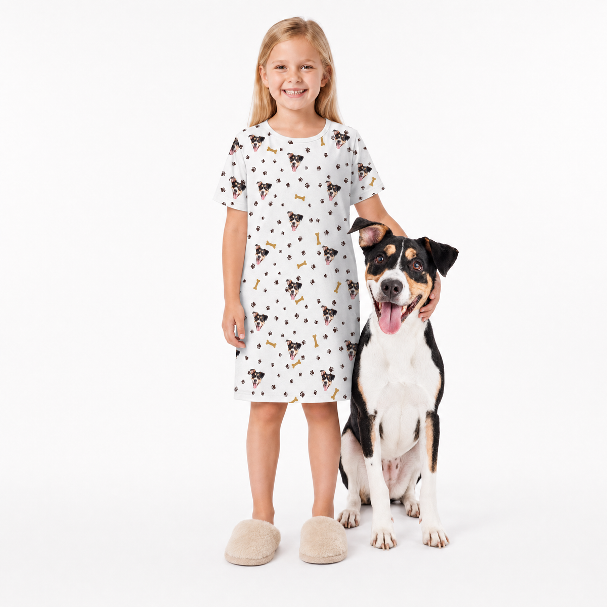 Girl wearing a white nightgown with dog print standing next to a dog on a white background
