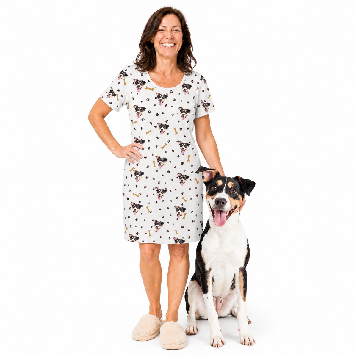 Woman wearing a dog patterned nightgown standing next to a dog on a white background