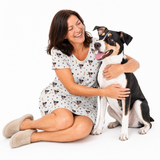 Paws and bones kids fleece blanket hoodie theme – person in dog-print dress hugging black‑and‑white dog.