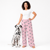 Woman wearing pink pajama pants with dog pattern standing next to a Dalmatian dog on a white background