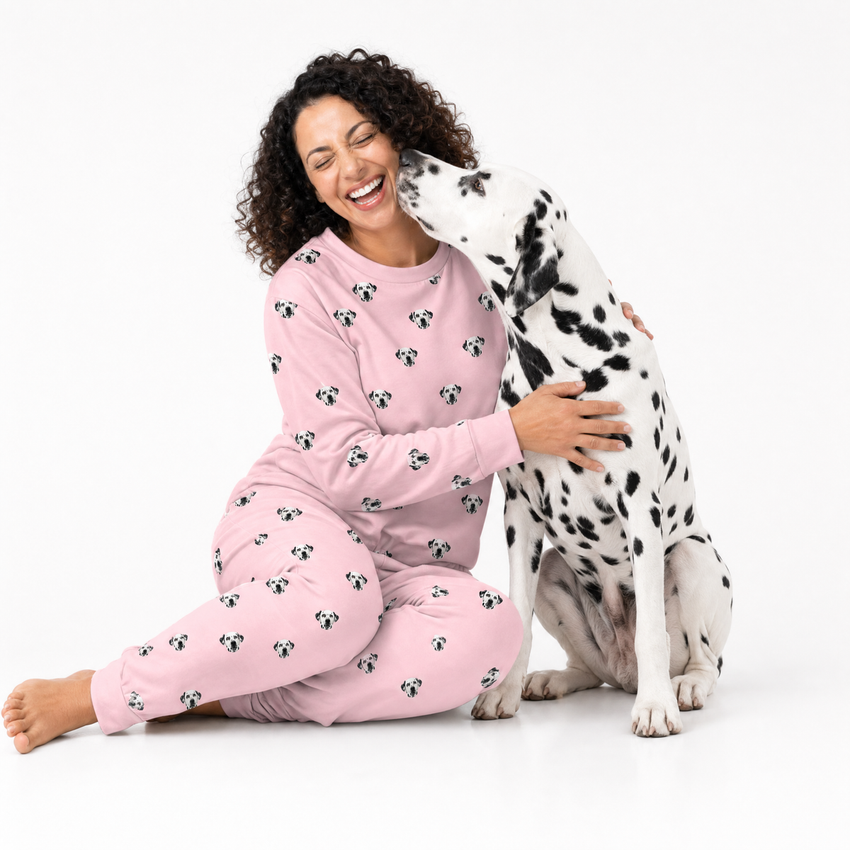 Woman in pink jogger pajamas with a Dalmatian dog on a white background