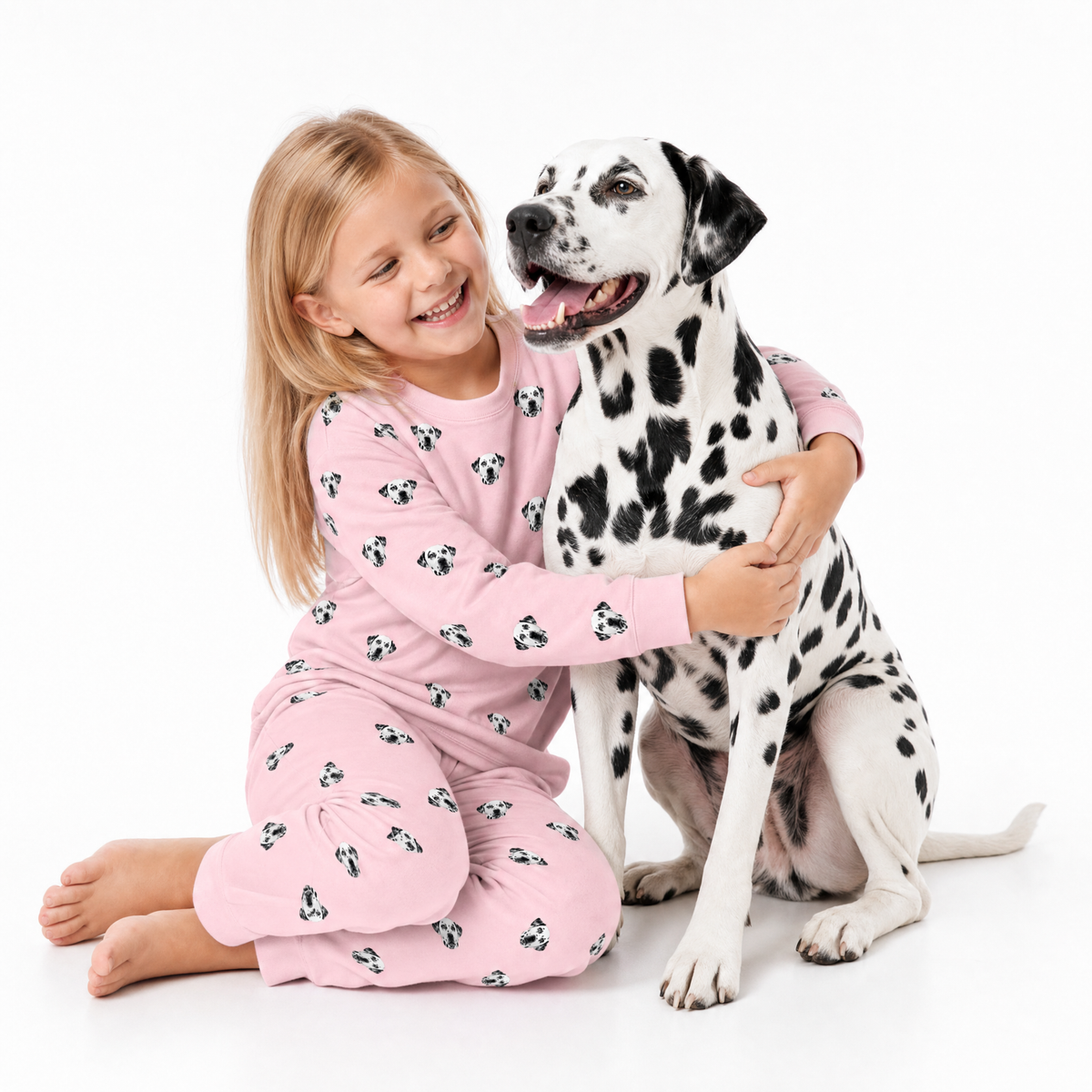 Child in pink jogger pajamas with a Dalmatian dog on a white background