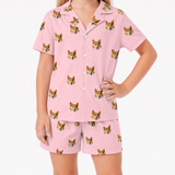 Pink pajama set with corgi pattern worn by a person on a white background