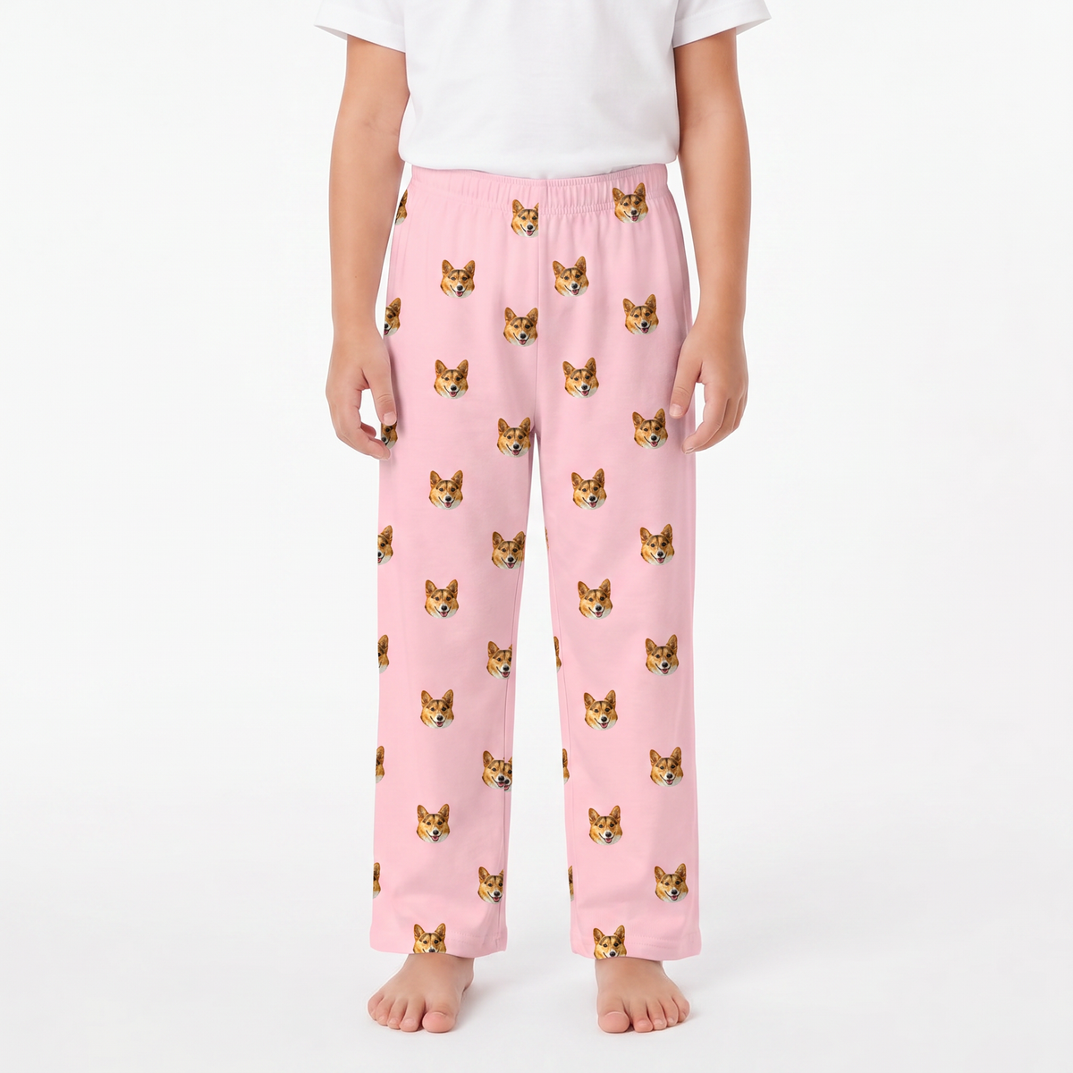 A child wearing pink lounge pants with a repeating pattern of small dog faces, paired with a white short-sleeve top, shown against a plain light background.