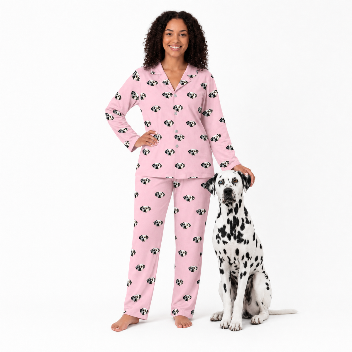 Woman wearing pink pajamas with a Dalmatian dog next to her on a white background