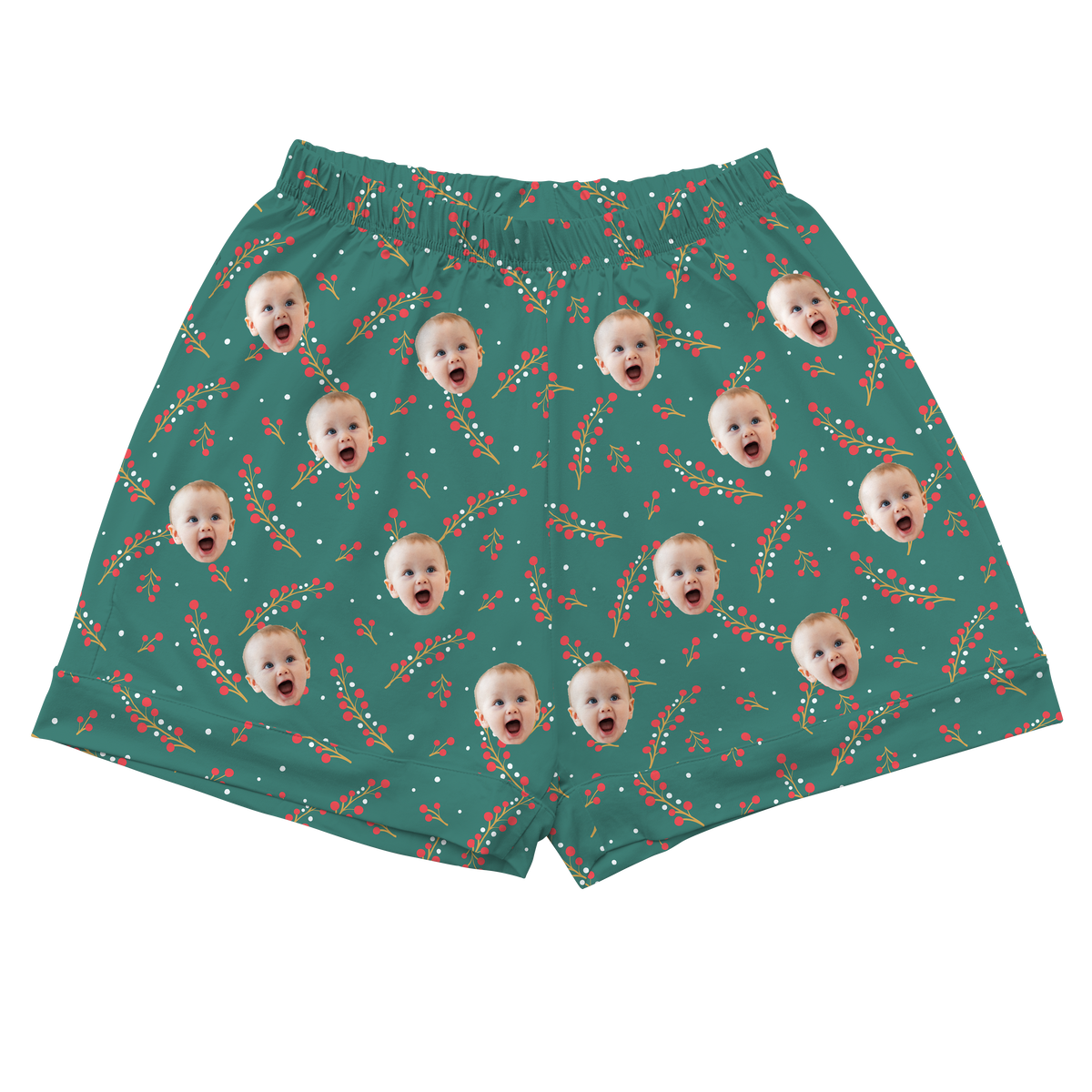 A pair of athletic or pajama shorts with an elastic waistband, featuring a teal background. The fabric is patterned with a festive design of repeating red berries on green stems, along with small white dots resembling snow or smaller berries. 