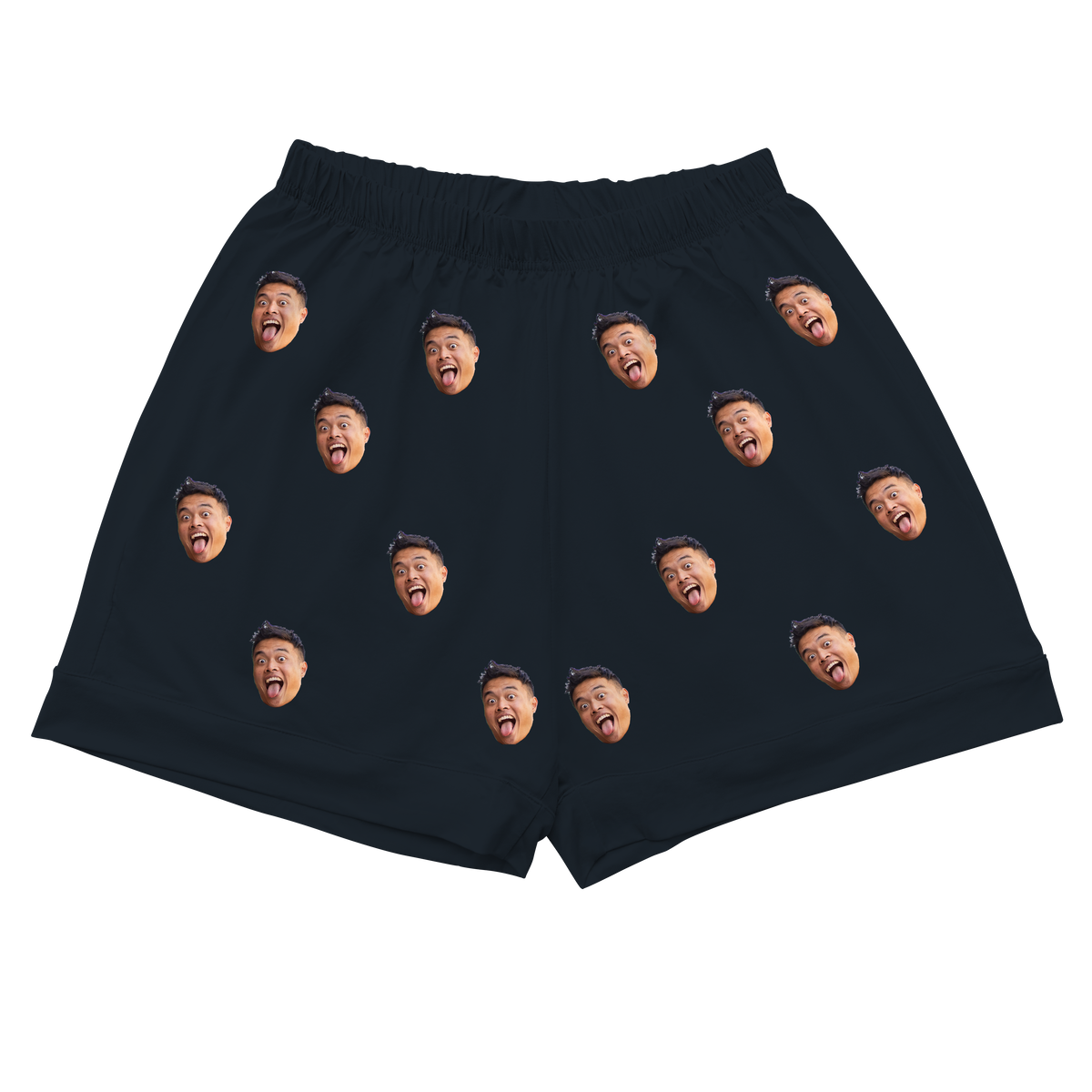 A pair of pajama shorts with a gathered, elastic waistband, made from a solid black fabric. Repeated headshots of a person's highly expressive face, with their mouth wide open and some sticking out their tongue, are evenly spaced and superimposed across the fabric. 