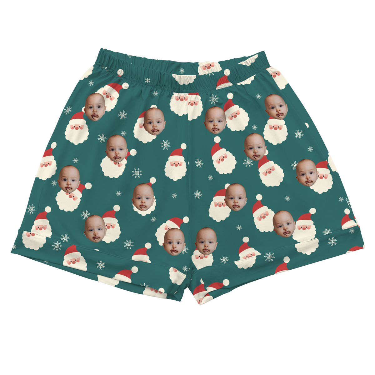 A pair of athletic or pajama shorts with an elastic waistband, featuring a dark teal or evergreen background. The fabric is patterned with repeating graphics of Santa's face with a red hat and white beard, interspersed with white snowflakes.