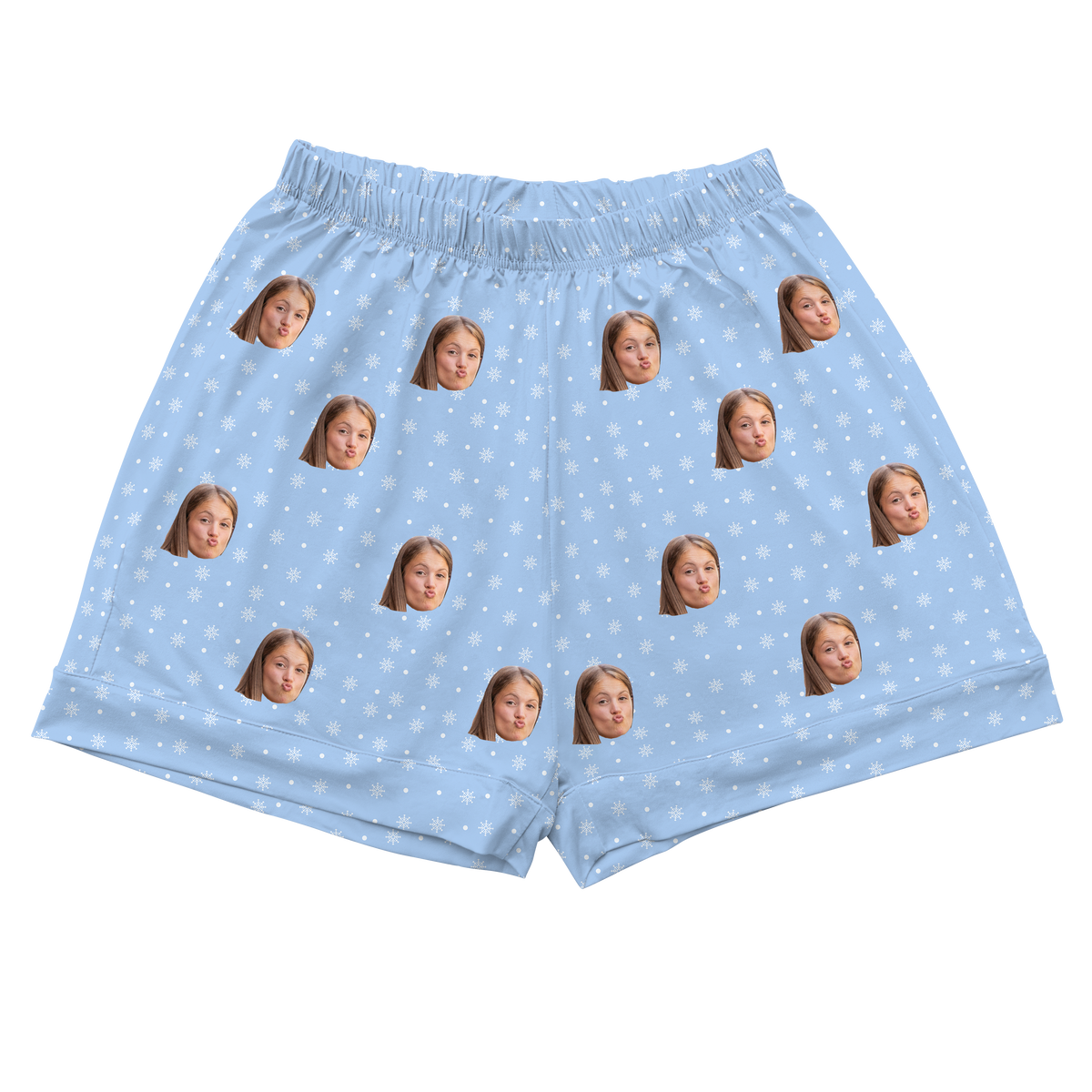 
A pair of light blue athletic or pajama shorts with a gathered, elastic waistband. The fabric is patterned with small white snowflakes and repeated headshots of a young girl's face.