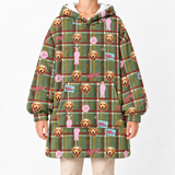 A person wearing a hooded sweatshirt dress with a green plaid pattern and an all-over print of golden retriever dog faces, pink bunny figures, and small blue and pink patches, shown against a plain light background.