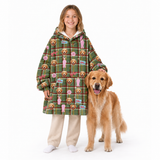 A young girl stands next to a golden retriever dog wearing a green plaid hooded sweatshirt covered in dog-themed illustrations, paired with beige pants and white socks, on a solid white background.