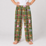 A person wearing green plaid pajama pants with a dog-themed print, standing barefoot against a light gray studio background.
