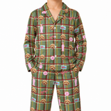 A person wearing a matching long-sleeve pajama set with a green plaid pattern, featuring cartoon dog faces, pink figures, and small novelty labels. The photo is cropped from the neck down against a plain white background.