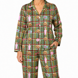 A model wearing a matching green plaid pajama set with a repeating pattern of golden doodle dogs, pink bows, and pink speech bubbles on a white background.