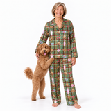 A woman wearing green plaid pajamas with a dog print stands barefoot on a white studio background, holding a small brown dog that is standing on its hind legs.