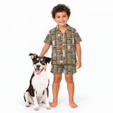 Young boy with curly hair standing next to a black, white, and tan dog, wearing a green plaid short-sleeve pajama set with custom dog face prints and pink bunny suit motifs.