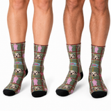 Three pairs of crew socks worn on legs, featuring a green plaid pattern with pink dog faces and pink doghouse motifs, black toes and heels, and small blue brand tags.