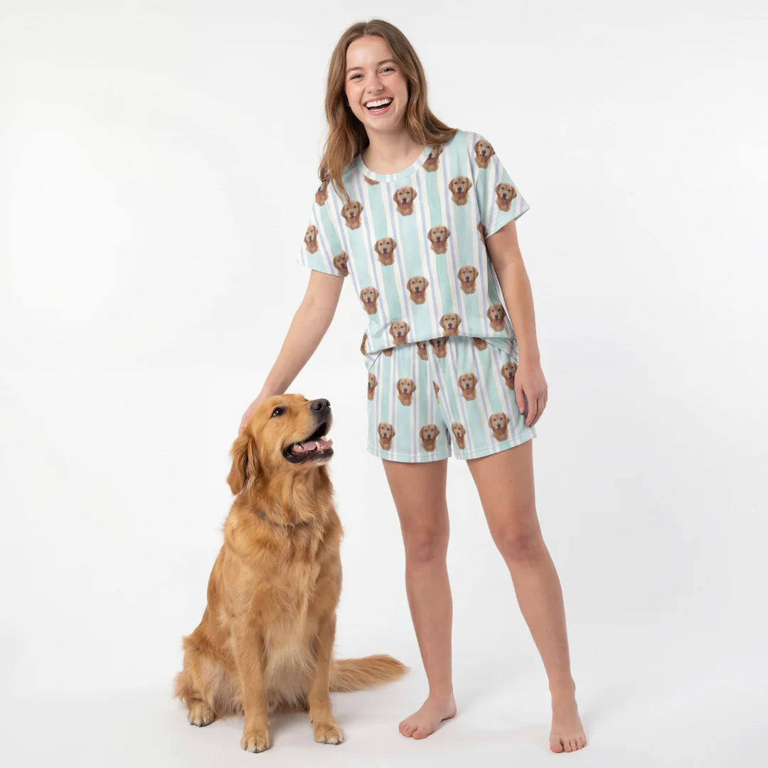 Woman wearing a dog-themed pajama set standing next to a golden retriever on a white background [MintStripes]