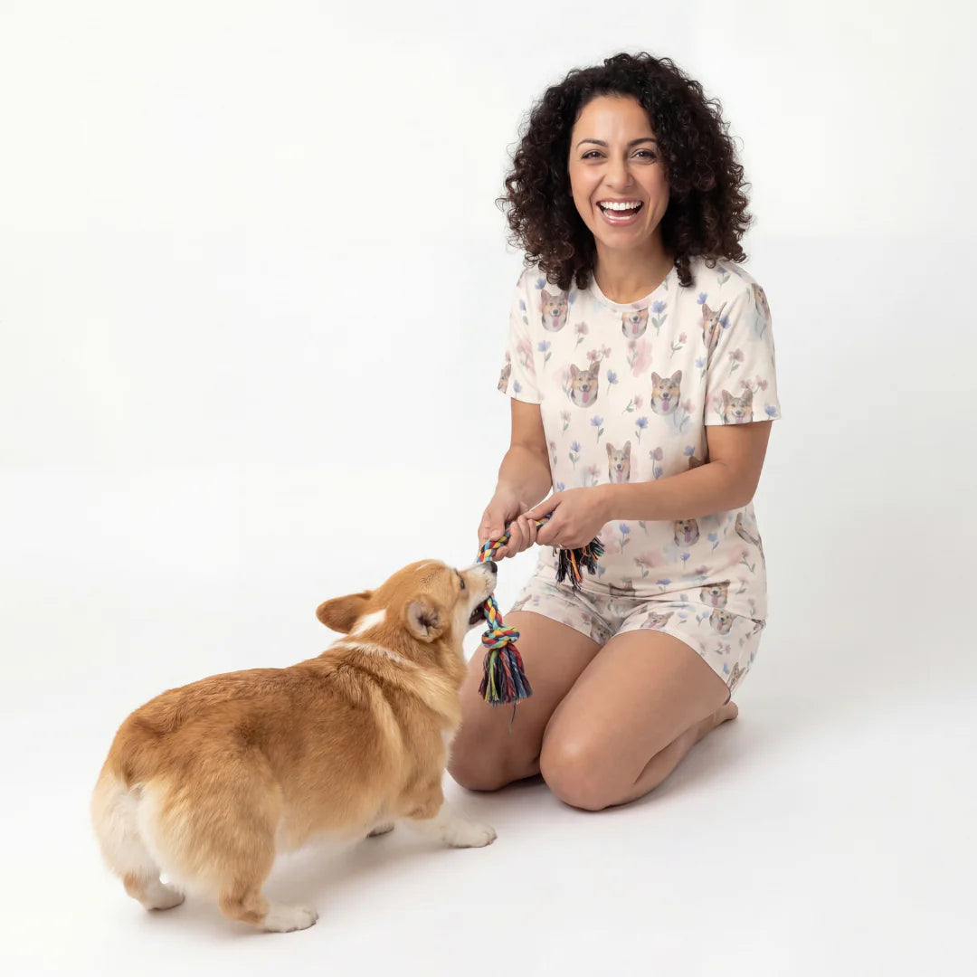 Woman in pajamas playing with a dog on a white background