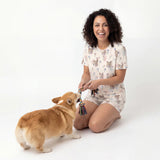 Woman in pajamas playing with a dog on a white background