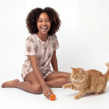 Woman sitting on the floor with a cat and a toy on a white background