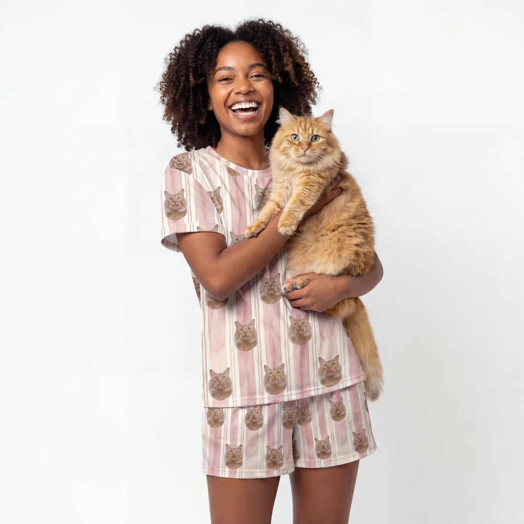 Woman wearing a cat-themed pajama set holding a cat on a white background [TerracottaStripes]