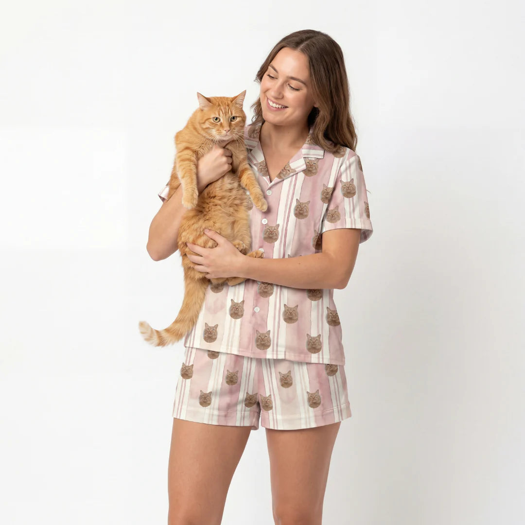 Woman wearing a pajama set with cat designs, holding an orange cat against a white background