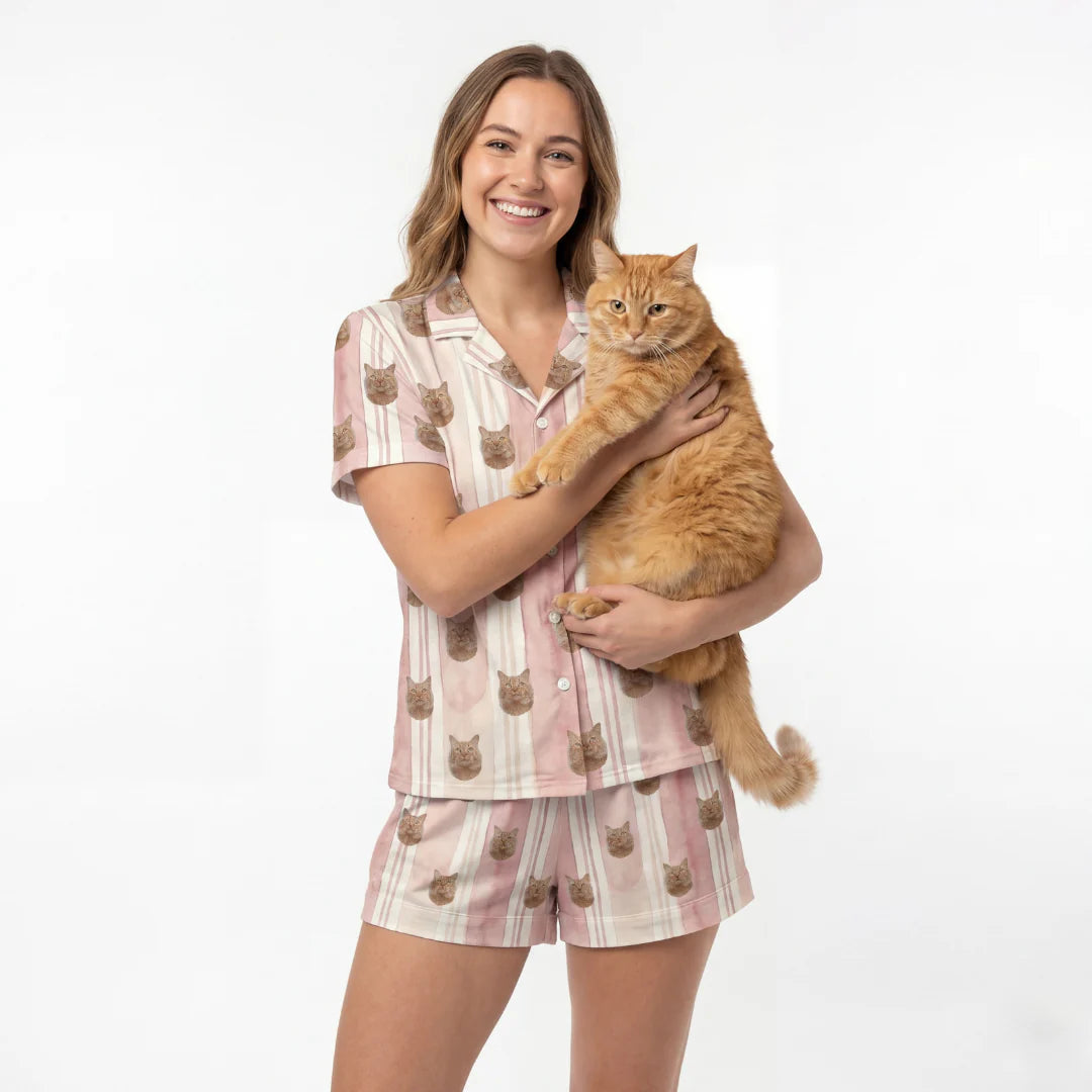 Woman wearing a pajama set with cat designs, holding an orange cat on a white background [TerracottaStripes]