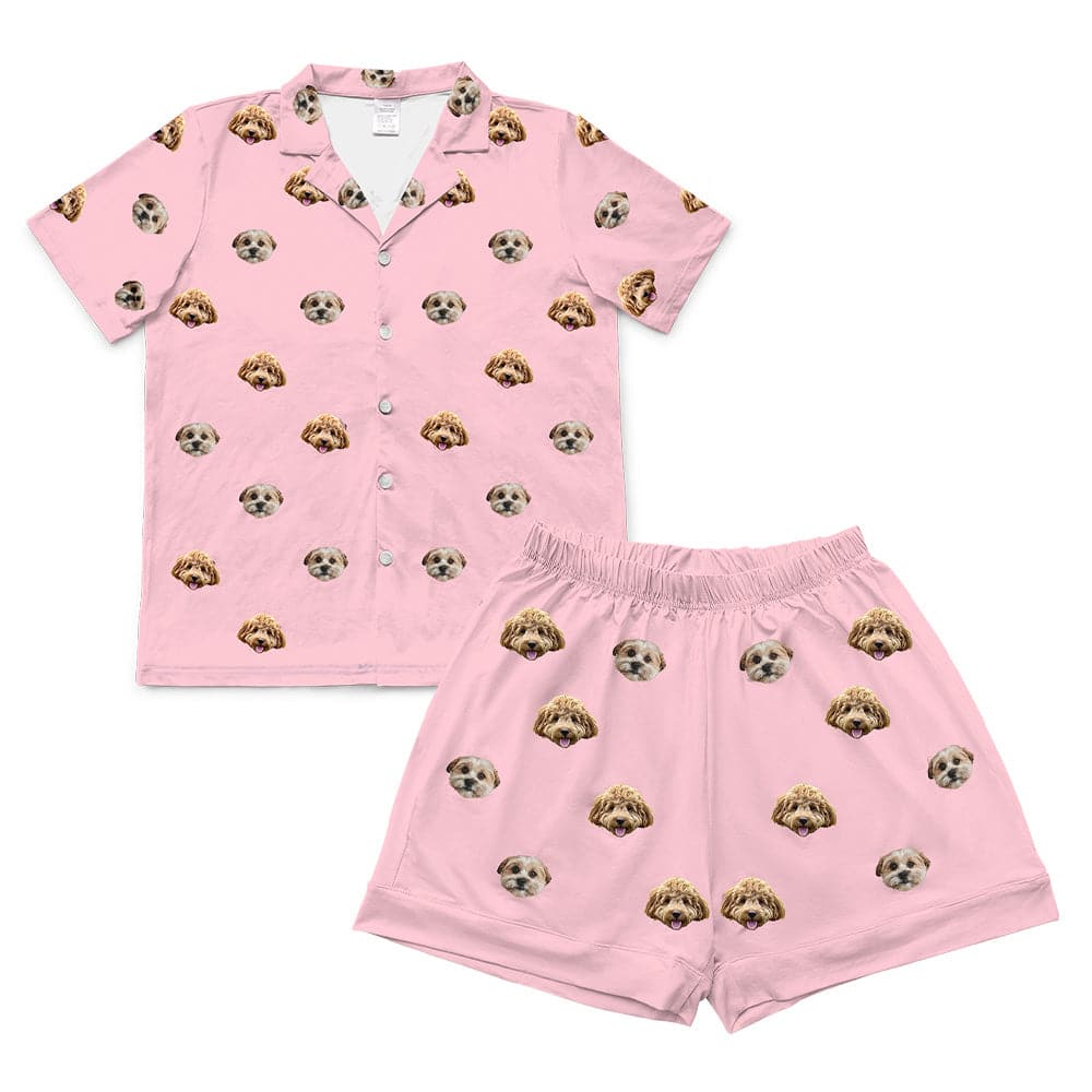 A matching short-sleeve pajama set in a light pink color. It features an all-over repeating pattern of the faces of two different small dogs.