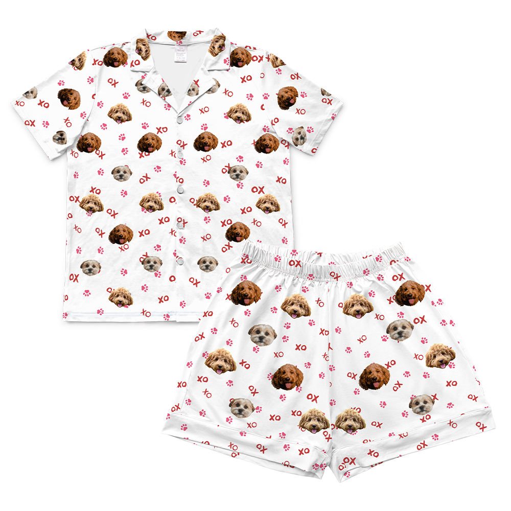 White short-sleeve pajama set with dog pattern and red XO and paw print designs on white background, includes button-up shirt and matching shorts
