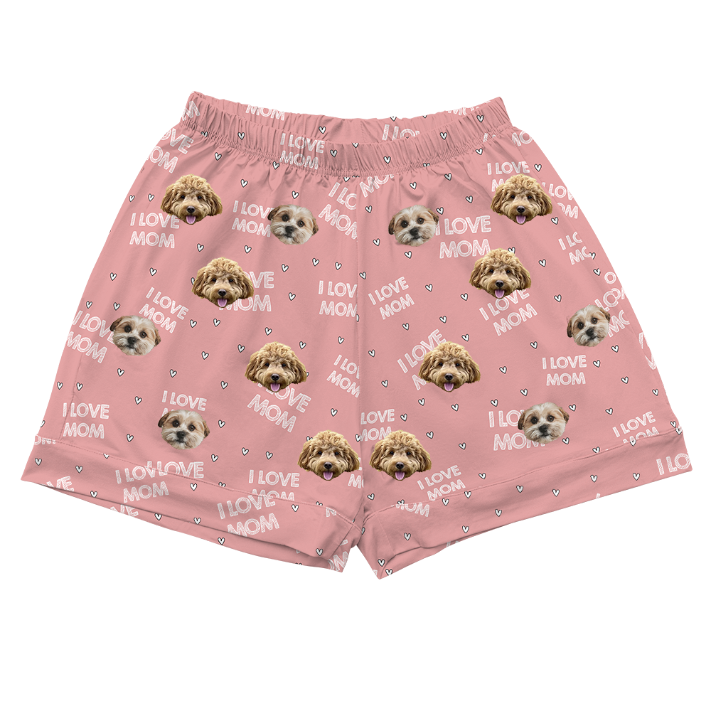 Light pink pajama shorts with an elastic waistband, patterned with the phrase "I LOVE MOM," tiny hearts, and the faces of two different dogs.
