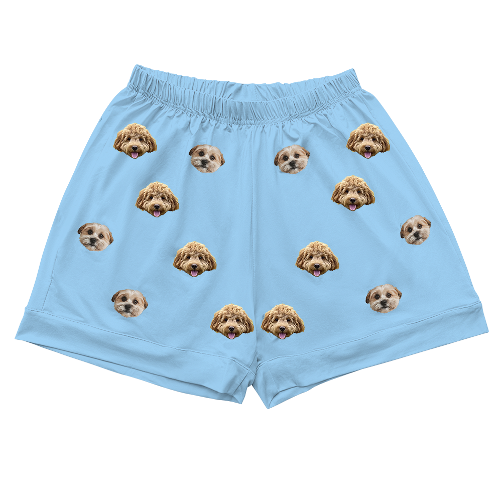 A pair of light sky blue pajama shorts. The shorts feature a repeating pattern of realistic photos of two different dogs' heads.