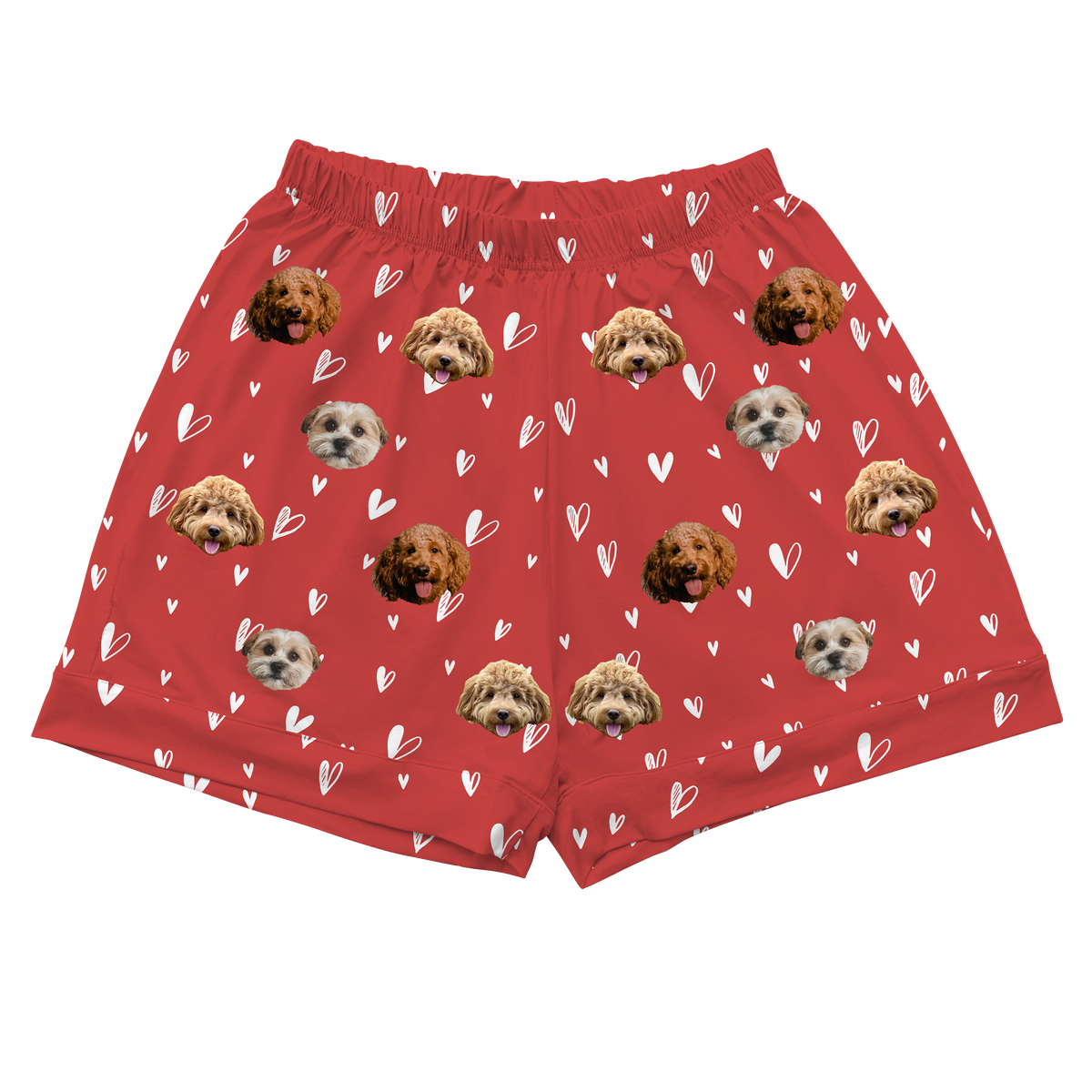 A single pair of short pajama shorts in a vibrant red color. The fabric is patterned with small, scattered white line-art hearts. Overlaid on this pattern are repeating, large, cropped dog faces, featuring three different types of dogs.