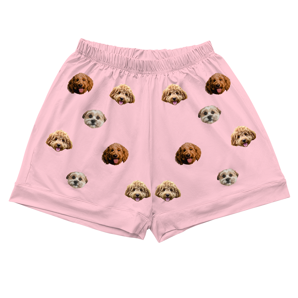 Pink shorts with an elastic waistband, featuring an all-over pattern of various dog faces.