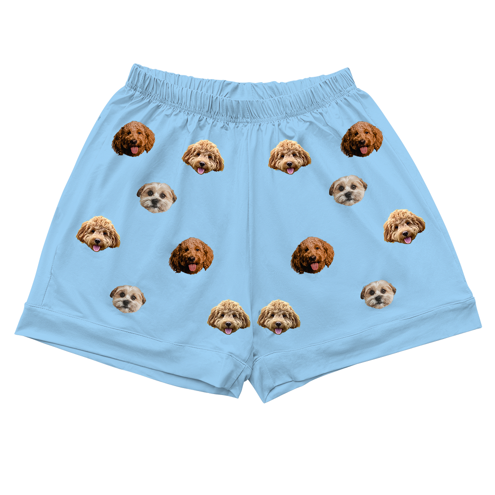 A pair of light sky blue pajama shorts. The shorts feature a repeating pattern of realistic photos of three different dogs' head.