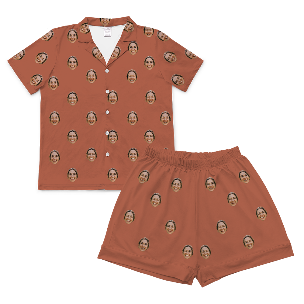 Cocoa-brown short-sleeve button-up pajama shirt with matching shorts, featuring a repeating pattern of the same smiling woman’s face across both pieces.
