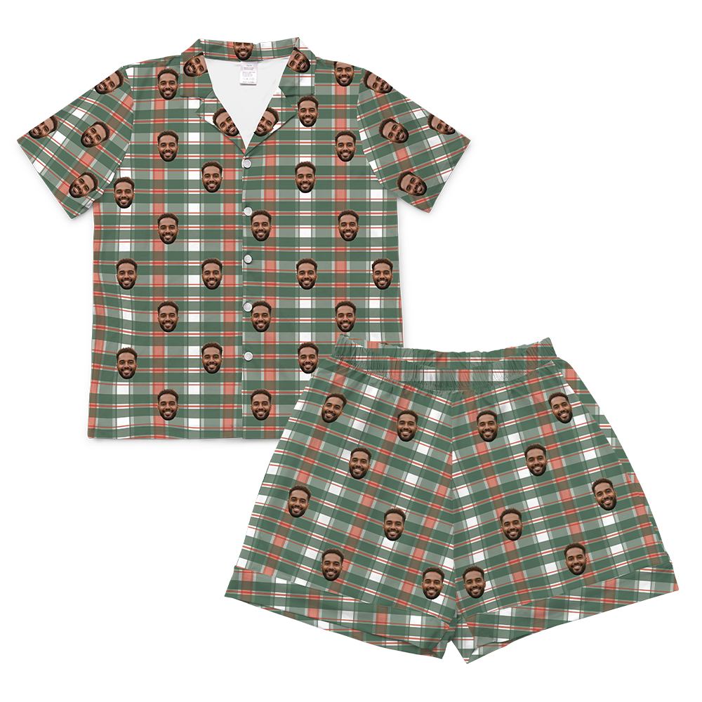 A two-piece set of short-sleeve pajamas in a festive plaid pattern of green, white, and orange/red. The pattern is customized with multiple small, repeating images of a man's smiling face covering the entire fabric of both the shirt and the shorts.