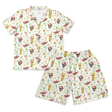 A two-piece kids' pajama set featuring a short-sleeve button-up shirt and matching shorts, both printed with a festive holiday pattern of Santa Clauses, martini glasses, candy canes, and snow globes on an off-white background.[ShortSleevePjs_Set_Men]