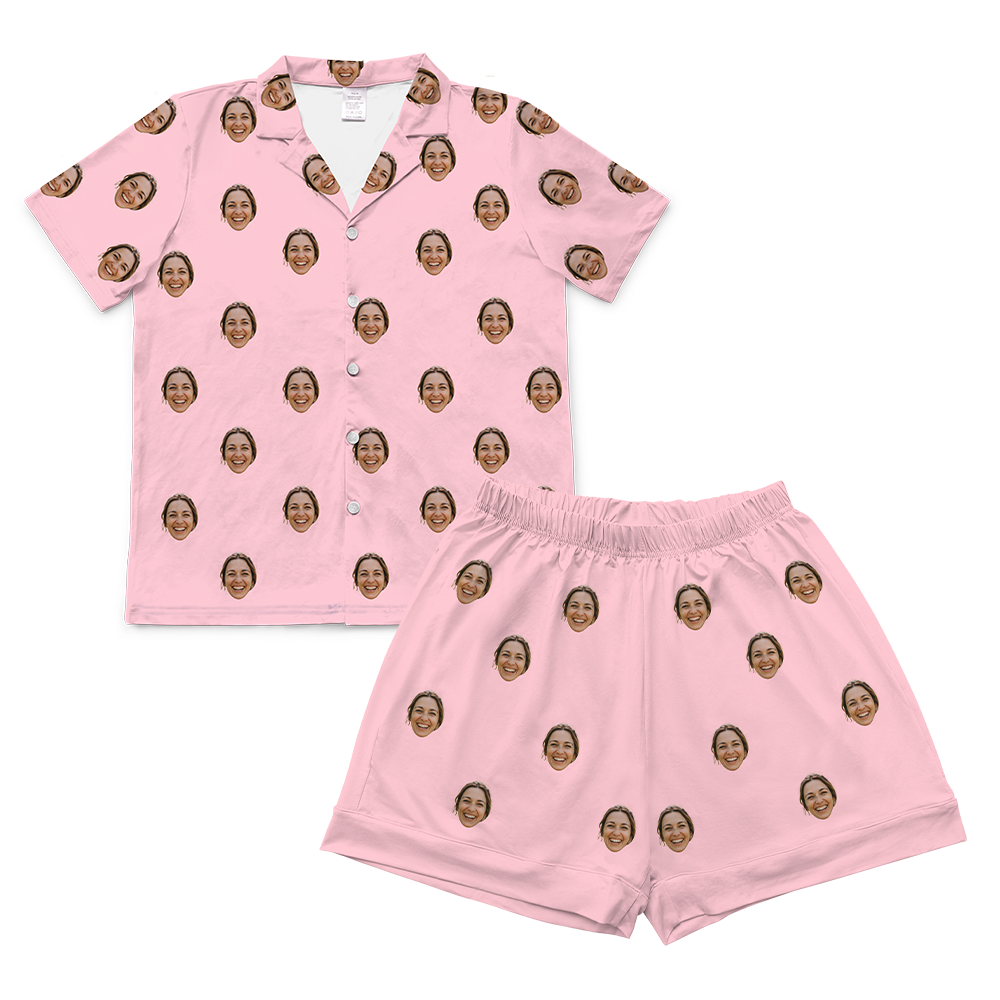 A two-piece set of short-sleeve pajamas in a solid bubblegum pink color. The pajamas are customized with multiple small, repeating images of a woman's smiling face covering the entire fabric of both the shirt and the shorts.