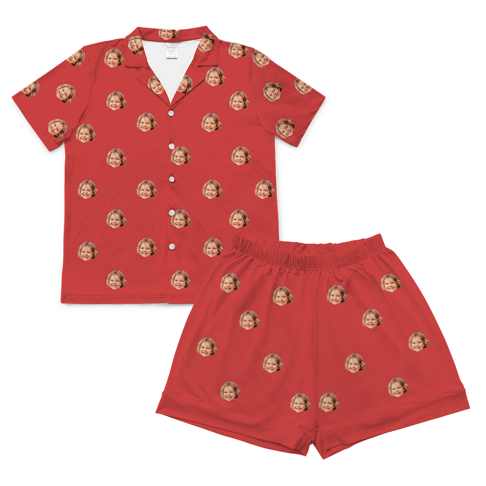 A two-piece set of short-sleeve pajamas in a solid bright red color. The pajamas are customized with multiple small, repeating images of a young girl's smiling face with blonde hair, covering the entire fabric of both the shirt and the shorts. 