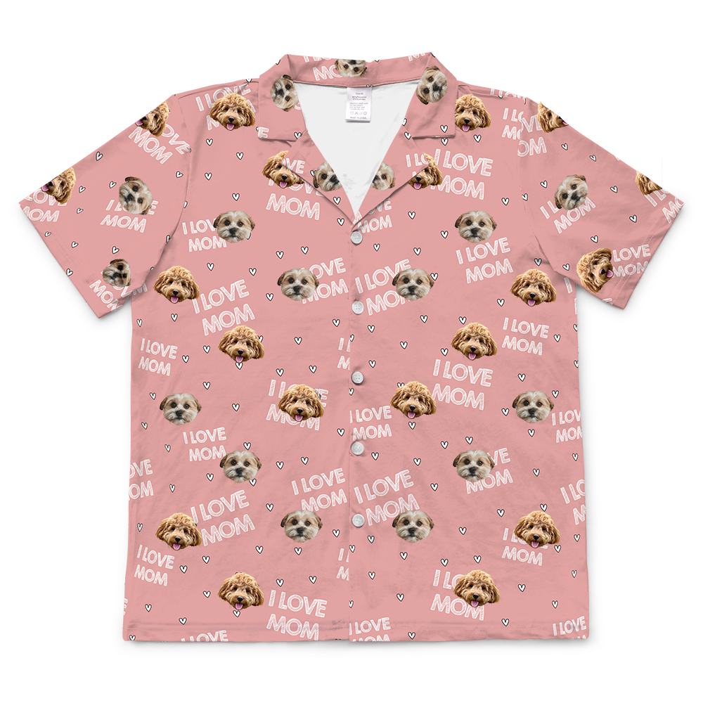 Pink short-sleeve button-up pajama top with an all-over pattern featuring two different dog faces, small white hearts, and the phrase “I LOVE MOM” repeated throughout.